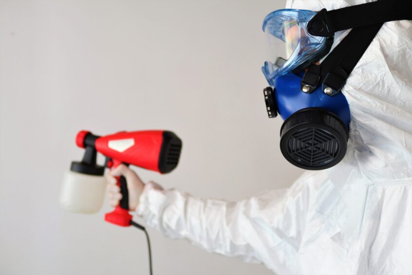 person doing mold removal with hazmat gear on